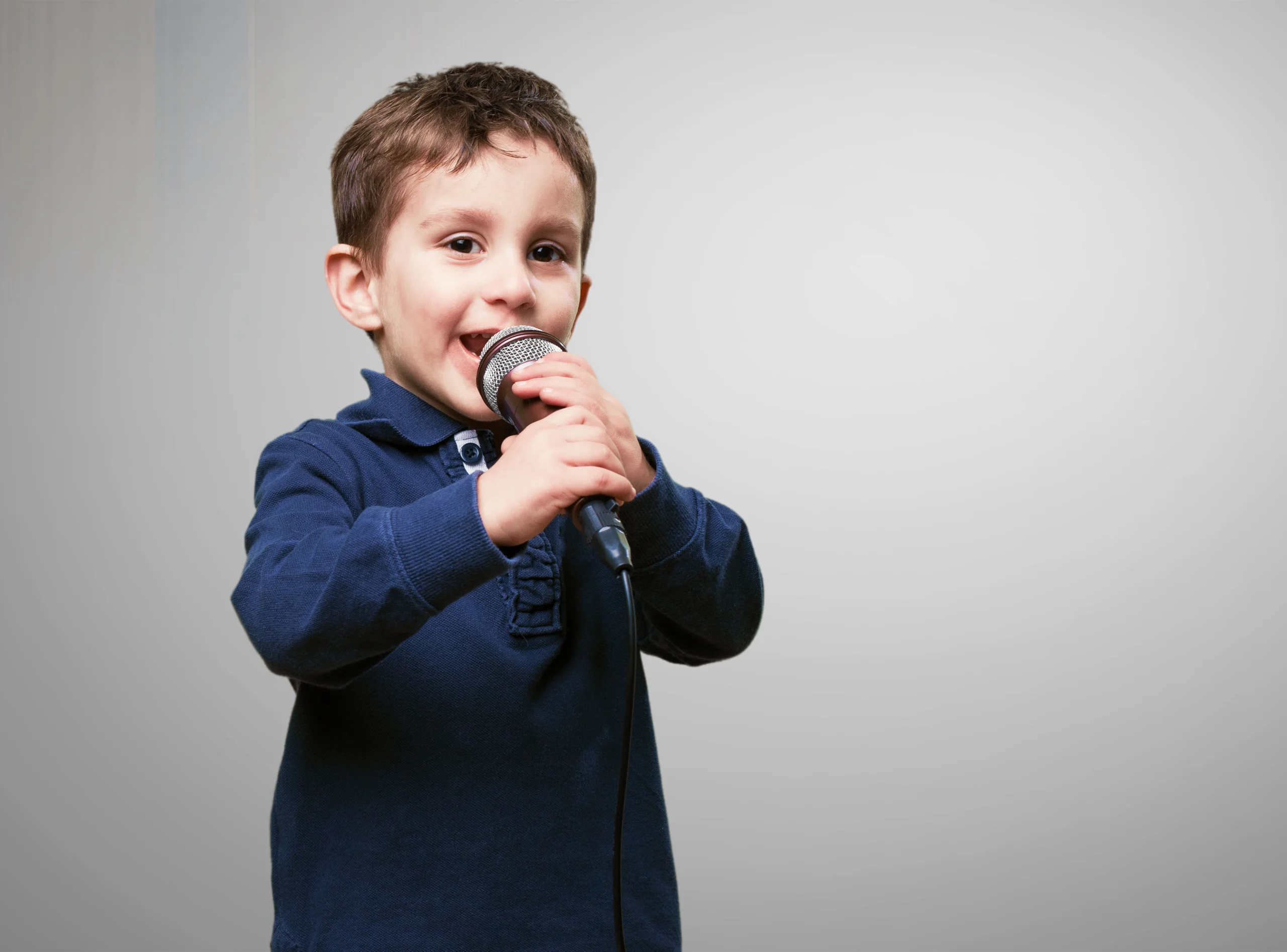 Child holding a microphone and smiling, showing confidence perfect for tips on how to speak in public.