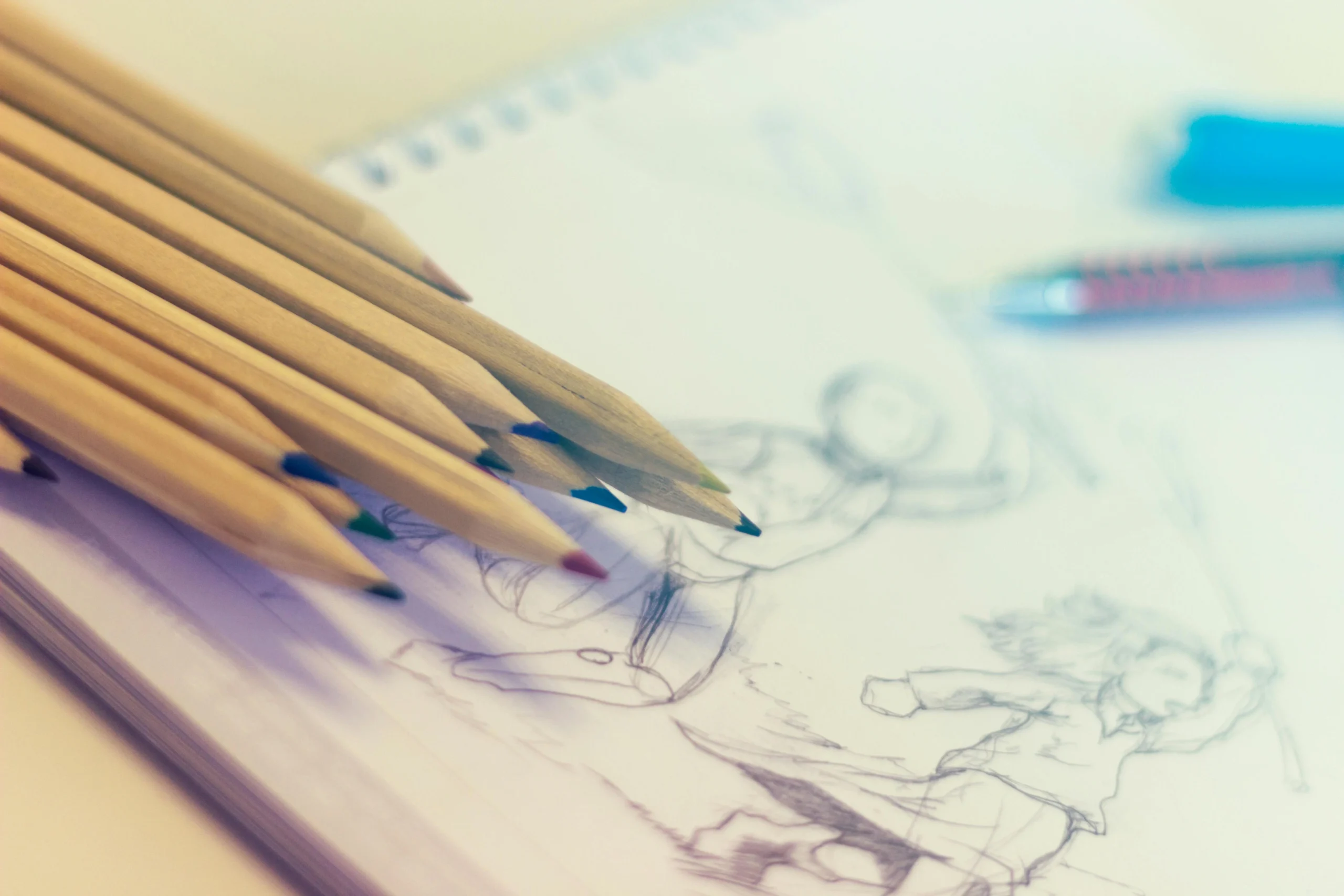 Colored pencils resting on a sketchpad with character drawings in progress, representing preparation for a drawing competition for students. Colored pencils resting on a sketchpad with character drawings in progress, representing preparation for a drawing competition for students. Colored pencils resting on a sketchpad with character drawings in progress, representing preparation for a drawing competition for students.